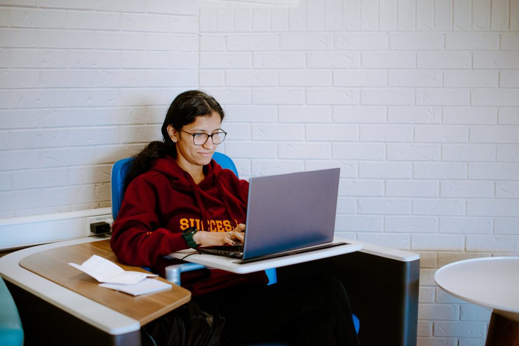 Female student in a chair on a laptop on campus